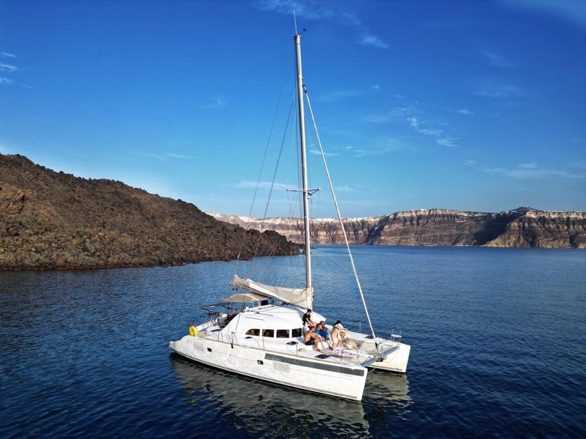 Santorini: Catamaran Cruise with Greek BBQ and Drinks - White Beach and Akrotiri views: caves, cliffs, and more swim time